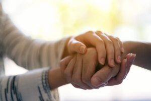 close up image of two people clasping hands demonstrating how repairing relationships with loved ones is possible