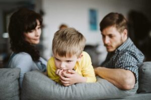 child sitting on couch turned away in fear from parents who are do not understand what is generational trauma and are perpetuating it