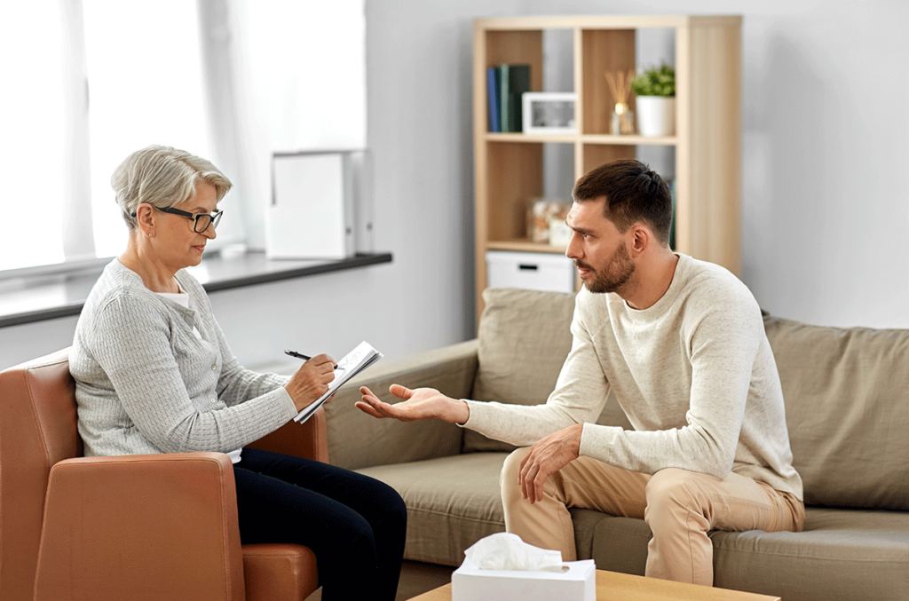 young man in an office setting speak to a therapist about the benefits of therapy