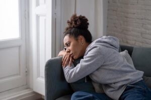 dad and depressed young woman sprawled despondently on couch showing signs of trauma in teens