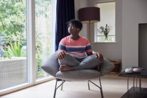 adolescent seated quietly off to themselves in a comfortable chair as one of 5 tips to calm social anxiety in teens.