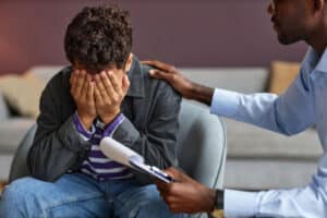 distraught teenage boy being consoled by a behavioral health specialist who is helping him to find a teen crisis intervention program in Omaha, NE.